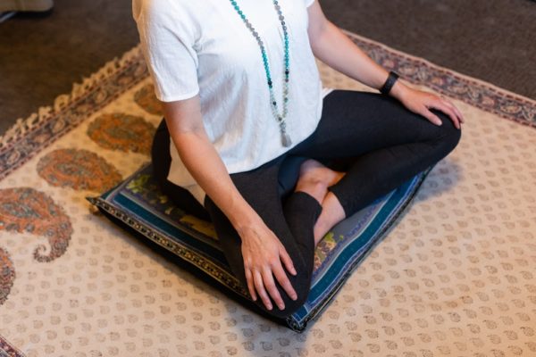 body of woman sitting in meditation on a cushion for yoga practice