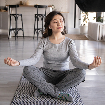 Woman meditating on a yoga mat in her home