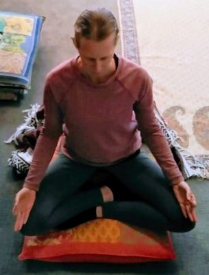 Woman sitting in meditation on a cushion