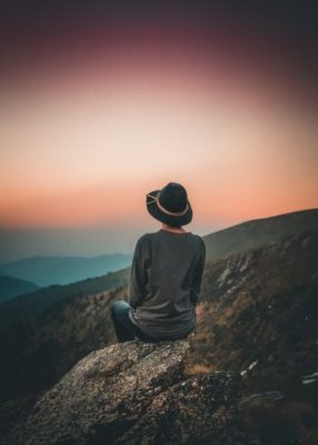 Woman on a mountain during sunset, pausing in contemplation