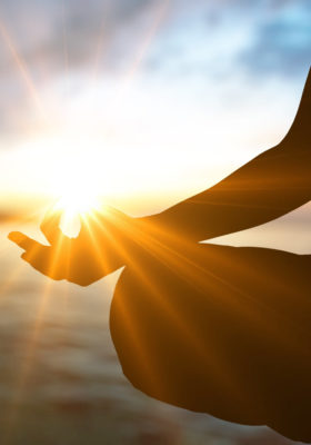 hand in chin mudra on right knee with sun brightly shining at the tip of thumb and pointer finger