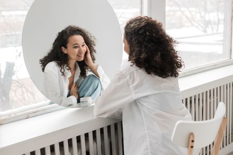 woman smiling at herself in a mirror