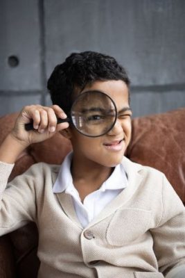 boy looking through a magnifying glass to observe