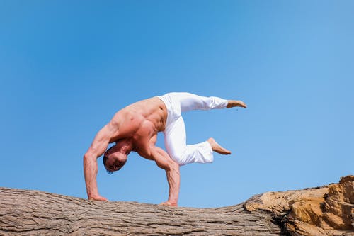 man in a challenging headstand position on a log