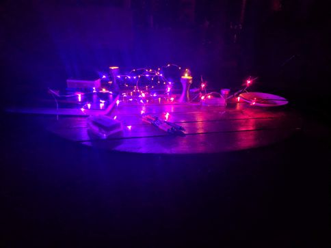 Purple Fairy lights and candles on a table in a dark room