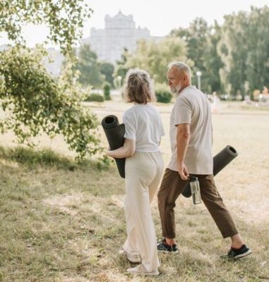 Man and woman walking in a park with yoga mats sharing an experience