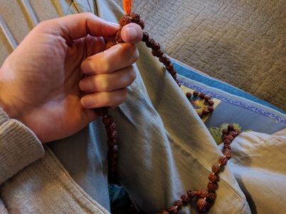 hand with a mala for repeating affirmation