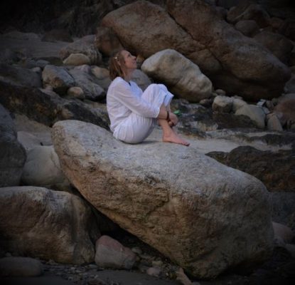 Woman sitting on a rock reflecting