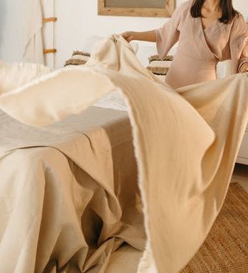 woman shaking out a sheet and the pause at the top