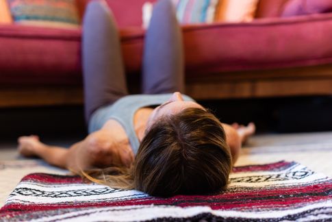 woman laying on floor with legs propped on a couch to relax