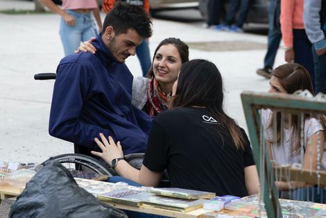 man in wheel chair looking sad surrounded by three supportive friends