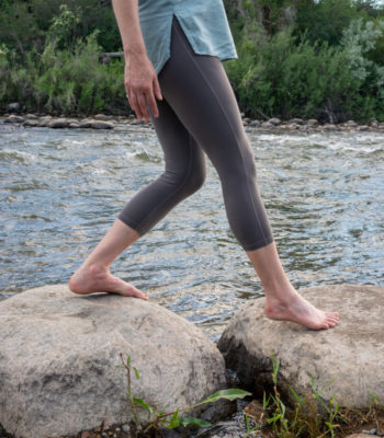 woman in mid-step from one rock to another in a process of moving forward