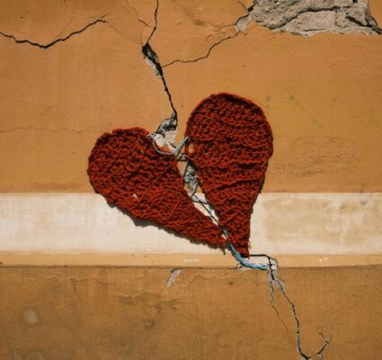 cracked wall with a knitted broken heart over the crack and heart being sewed up