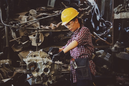 woman machinist working on a machine in yellow hard hat