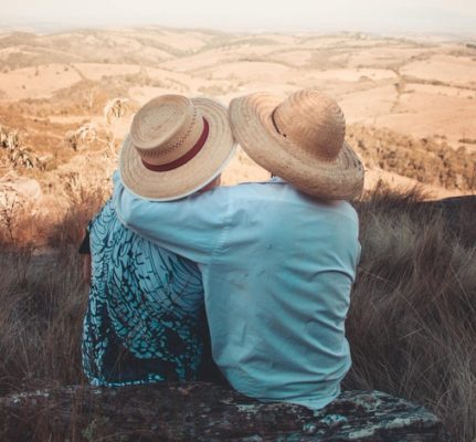 Two people sitting on an overlook, one with arm around the other supporting