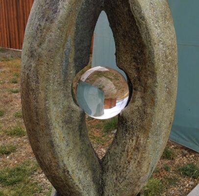 oval sculpture with a glass ball in the center reflecting the background upside down representing different perspectives