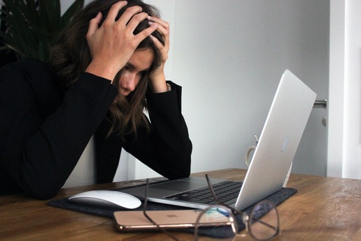 business woman with hands on head looking at computer in stress