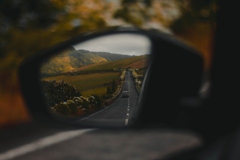 looking into sideview mirror to see the road of the past