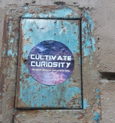 circle sticker that says cultivate curiosity on cement wall