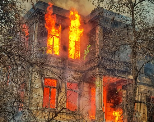 two story home on fire with flames and smoke coming from the window