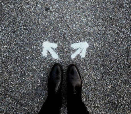 person's fee in black shoes with two arrows on the road in front of them giving them a choice into which way to go