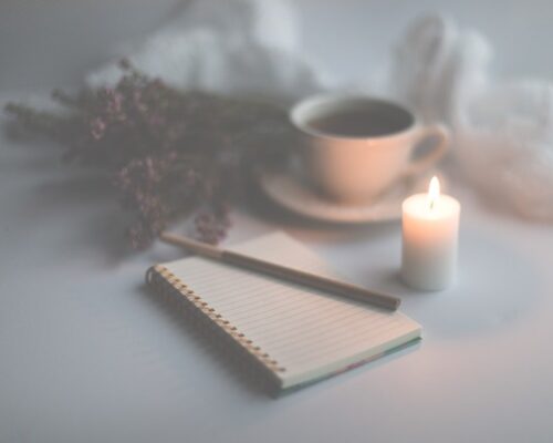 blank journal with pen, candle, hot tea and flowers, ready for inspiration