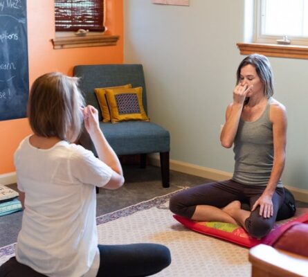 Woman being led by a yoga based counselor in how to do alternate nostril breathing in her office