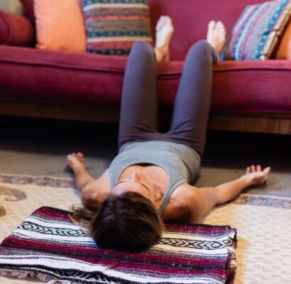 woman lying down with lower legs and feet supported on a couch called constructive relaxation pose