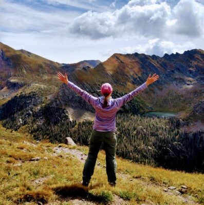 Woman standing outside looking out over mountains with arms outstretched in joy