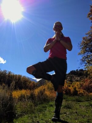 woman in tree pose with bright sun and fall colors, a pose of focus and concentration