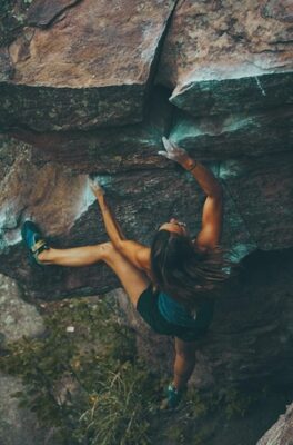 woman bouldering and going for a hard move with a long fall potential