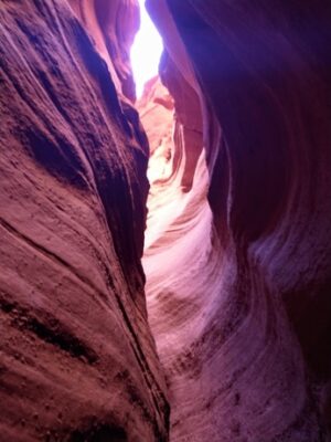 bottom of a slot canyon looking up through the orange layers into the light