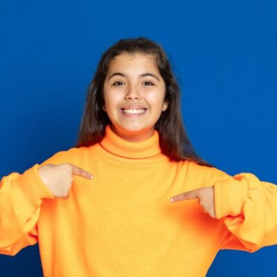 Young woman smiling and pointing at herself as she enjoys understanding herself