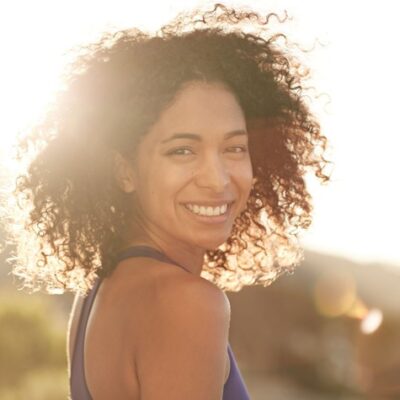 woman smiling with joy and contentment, sun shining behind her