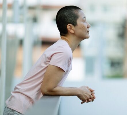 person leaning on a railing with eyes closed and breathing through the nose to calm the mind