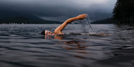 Person swimming outside with stormy skies