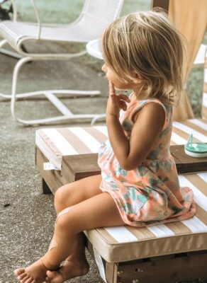 small girl sitting with finger on her cheek, thinking with curiosity