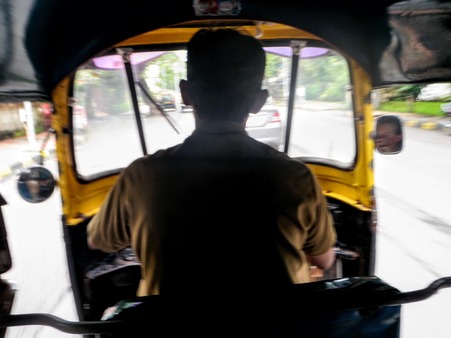 back of a man driving an autorickshaw in India