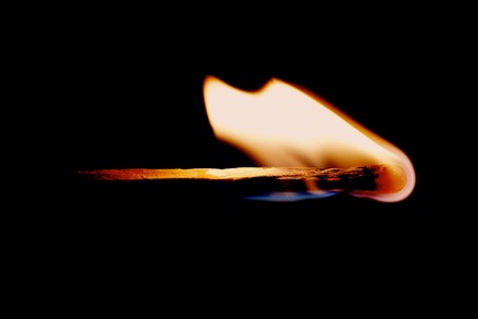 close up of a match burning against a black background signifying the burning of Tapas