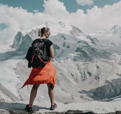 young woman pausing to look at a spectacular snow-capped mountain view in her hiking adventure