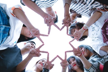 eight people in a circle creating an 8-sided star with their peace fingers looking up through the shape of connection