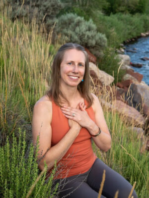 Headshot of author with hands on the heart by a river