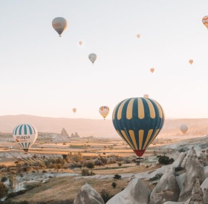 hot air balloons just lifting off the ground while others are high in the sky