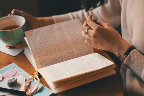 woman's hands journaling with a cup of tea as she sets her resolve