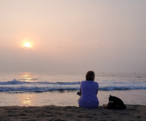 woman sitting in reflection on a beach at sunset