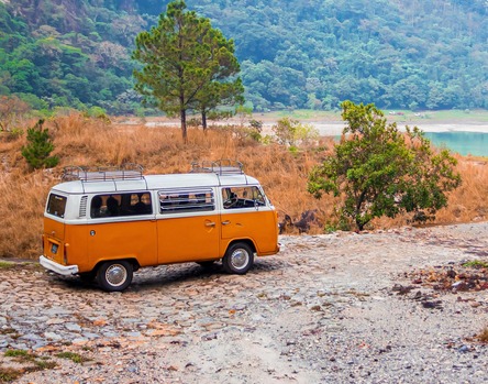 orange VW van driving to a lake
