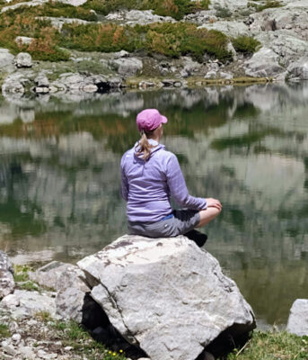 Author sitting still by a lake practicing yoga