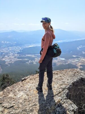 Author smiling at the top of a hike over looking the valley below