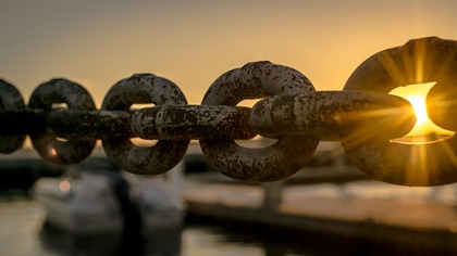 metal chain with sunset in background representing a kinetic chain so as one link moves it effects the entire chain