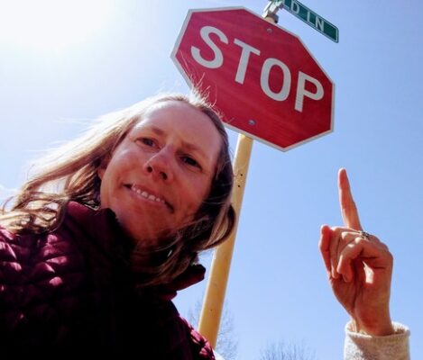 Author pointing to a stop sign as a reminder to pause when you are aware of a noisy mind reaction